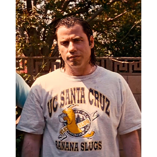 Image of Vincent Vega wearing the iconic Santa Cruz t-shirt from Pulp Fiction. This high-quality t-shirt made from 100% cotton offers a comfortable and relaxed fit, and features an exclusive design that combines the classic Santa Cruz logo with an unmistakable reference to the legendary character played by John Travolta